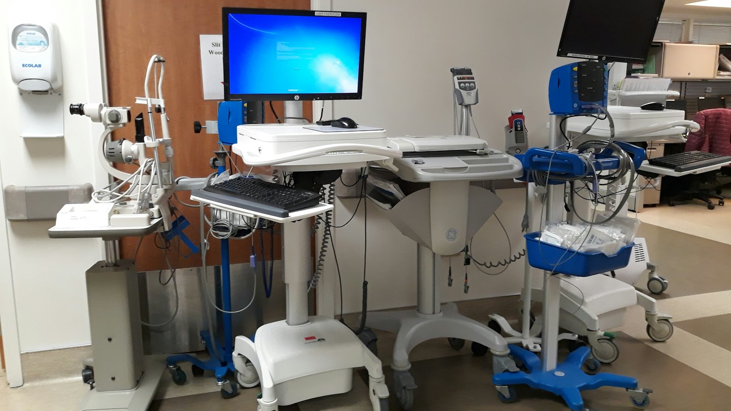 Medical equipment on wheeled carts positioned in a clinic hallway.