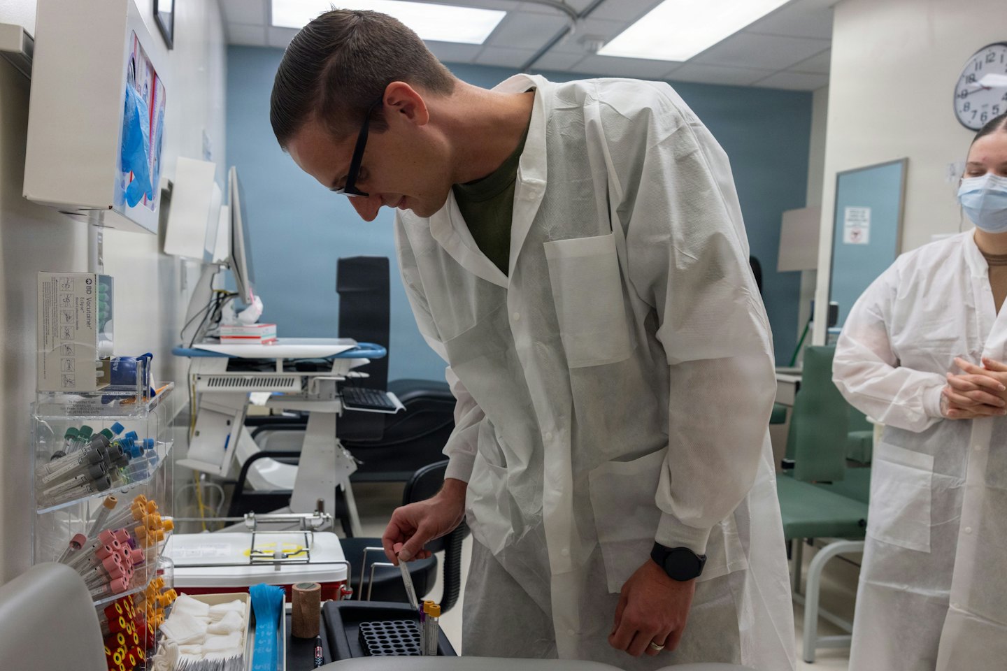 Medical professional examines a test tube at a lab workstation.