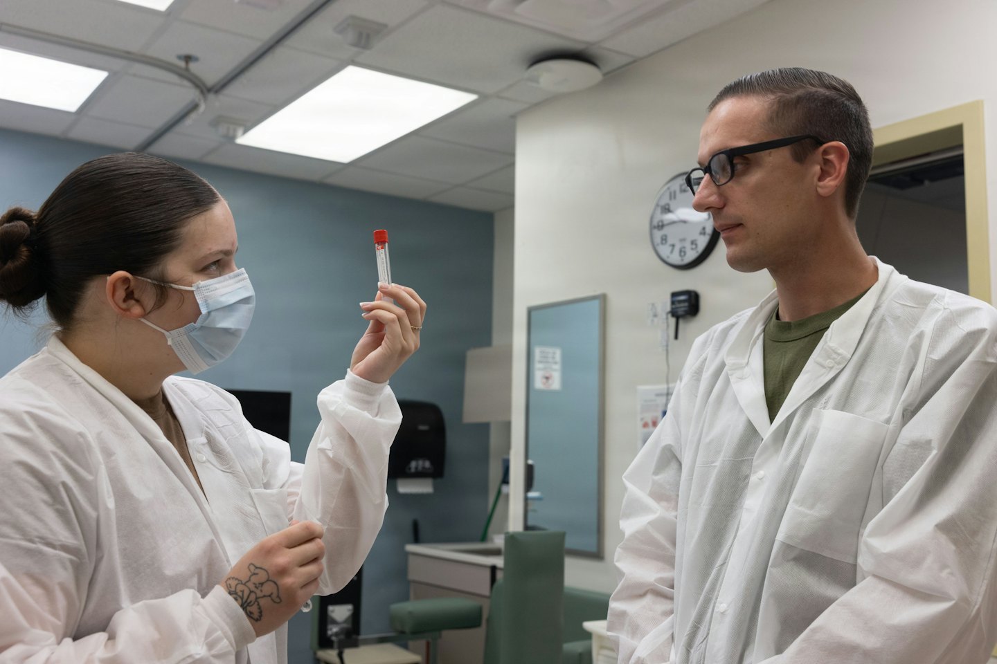 Two healthcare professionals examine a test tube in a lab.